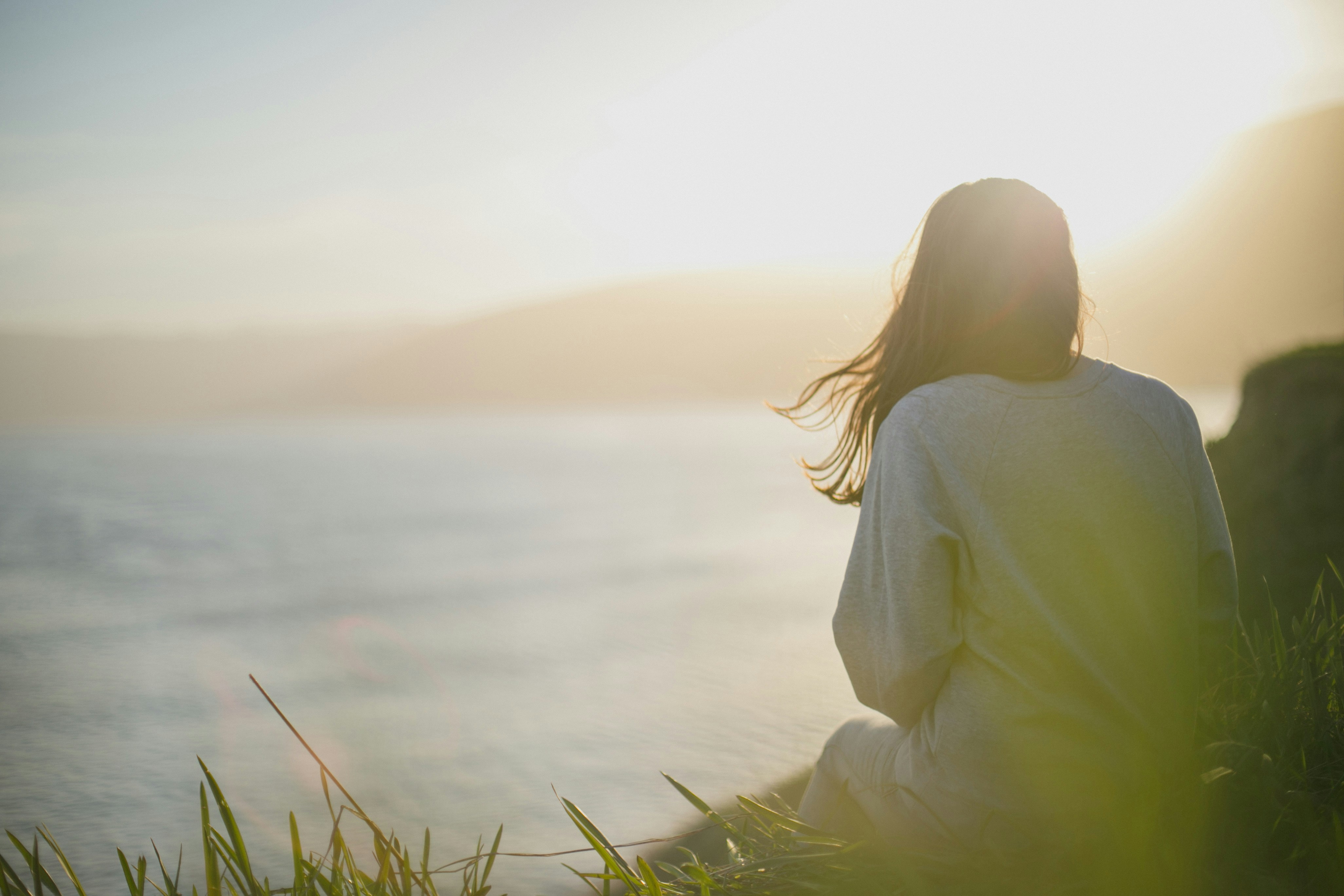 Femme méditant au bord de l'eau au coucher du soleil